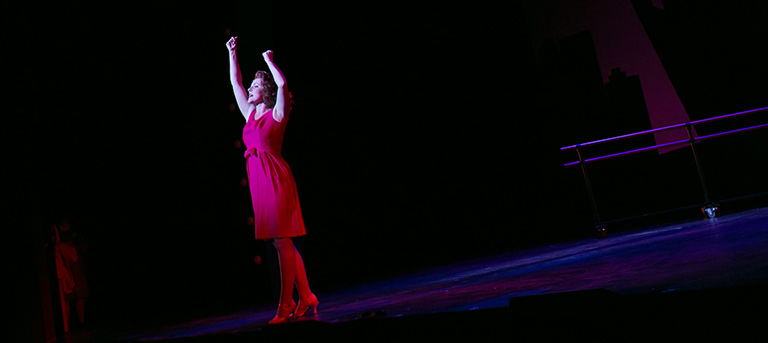 An actress sings on stage, alone.